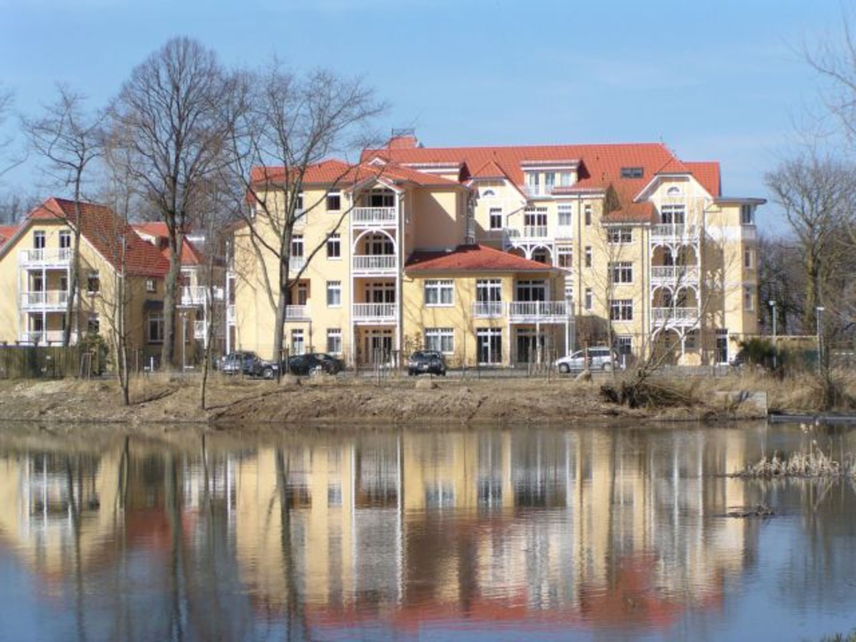 Idyllische Süd-Ansicht des Dünenschlosses mit Blick auf einen kleinen See und den Stadtwald 