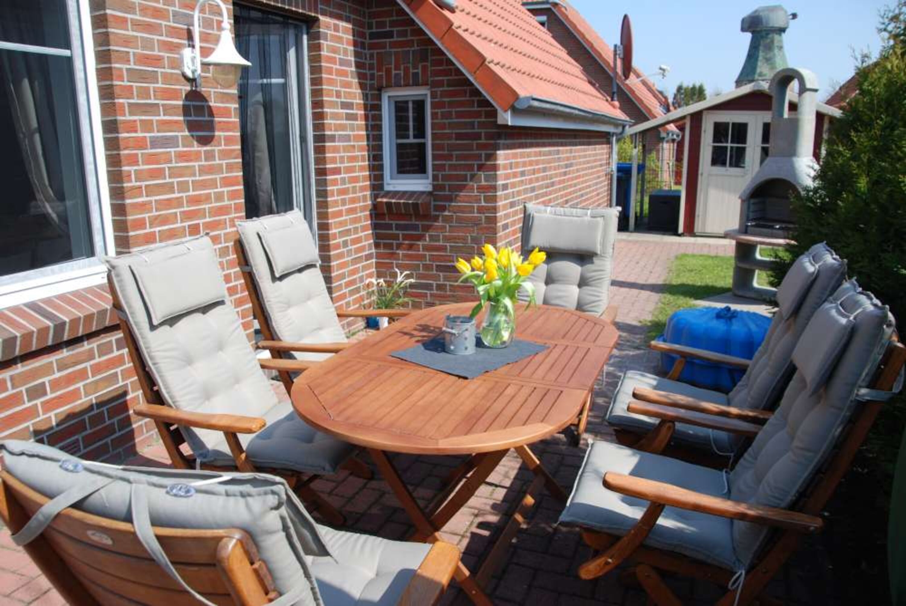 sonnige Terasse mit Gartenmöbeln, Sonnenliegen, Grillkamin, kleinem Sandkasten, Garten 1,20m hoch eingezäunt