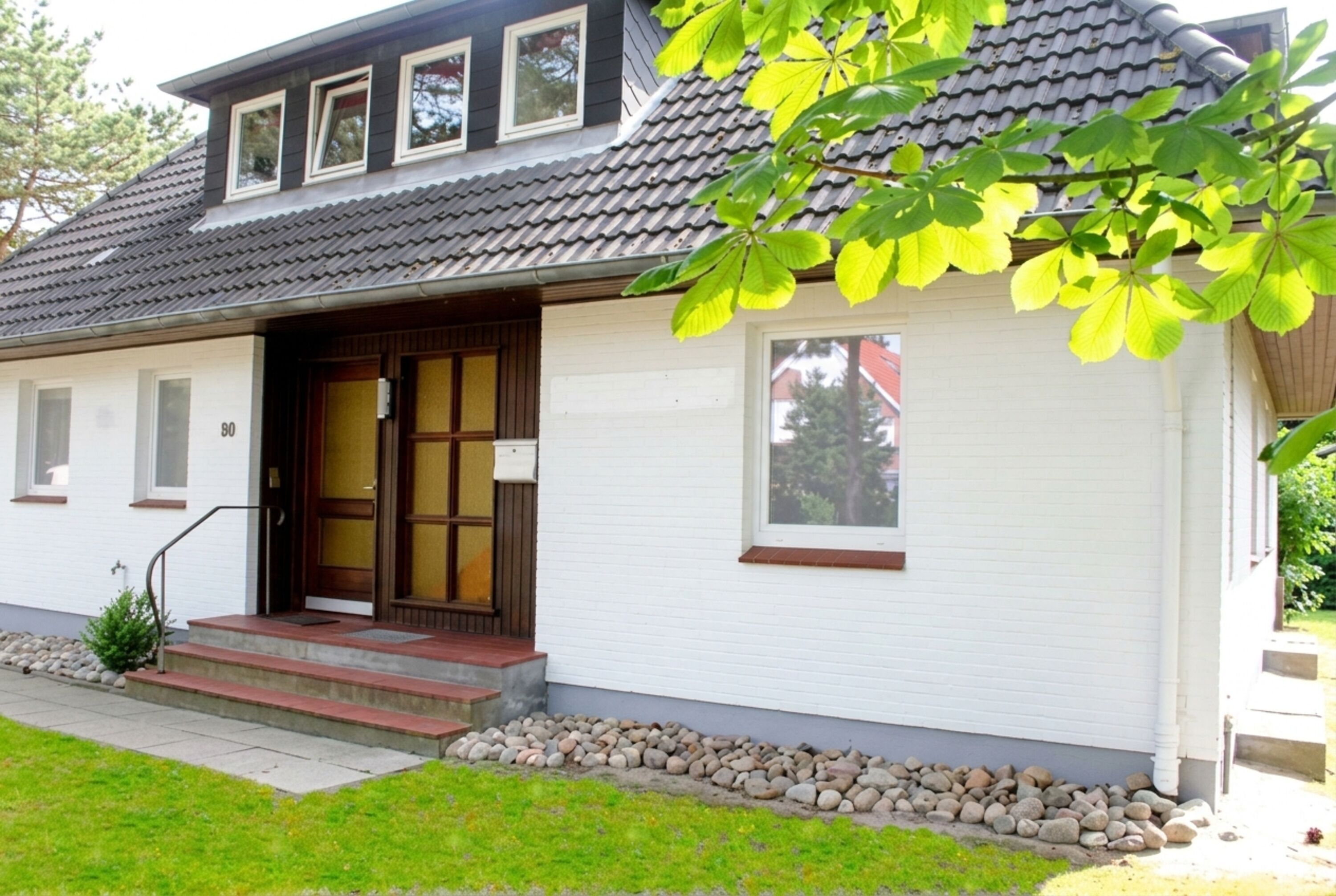 die Strandmuschel - ein schickes Ferienhaus mit zwei separaten Wohnungen - rundherum gibt’s gepflegtes Grün und schattige Bäume.