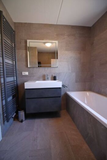 Badezimmer mit Badewanne, Waschbecken, beleuchteter Spiegel, Regendusche