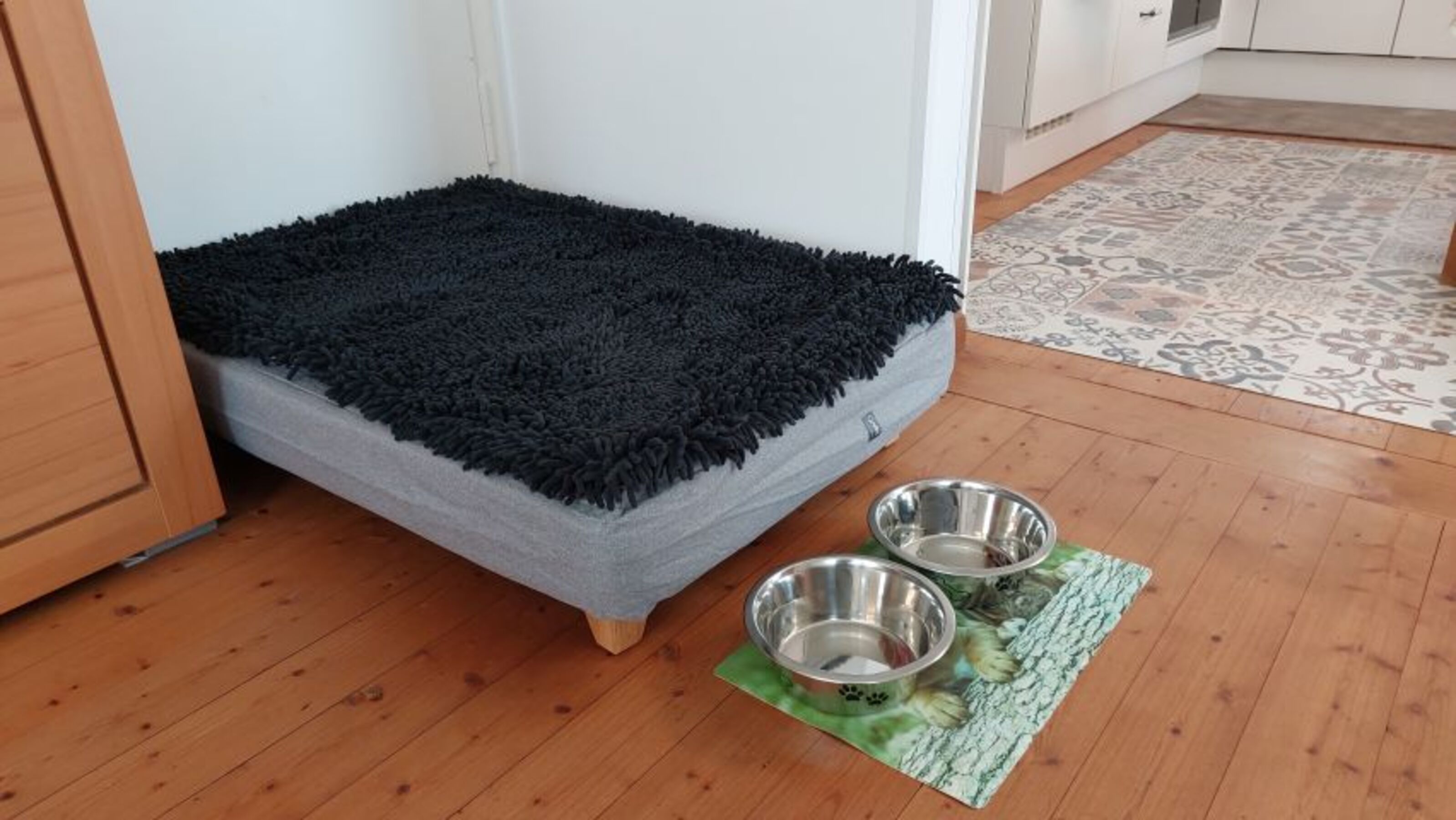 großes Hundesofa und Näpfe stehen bgereit