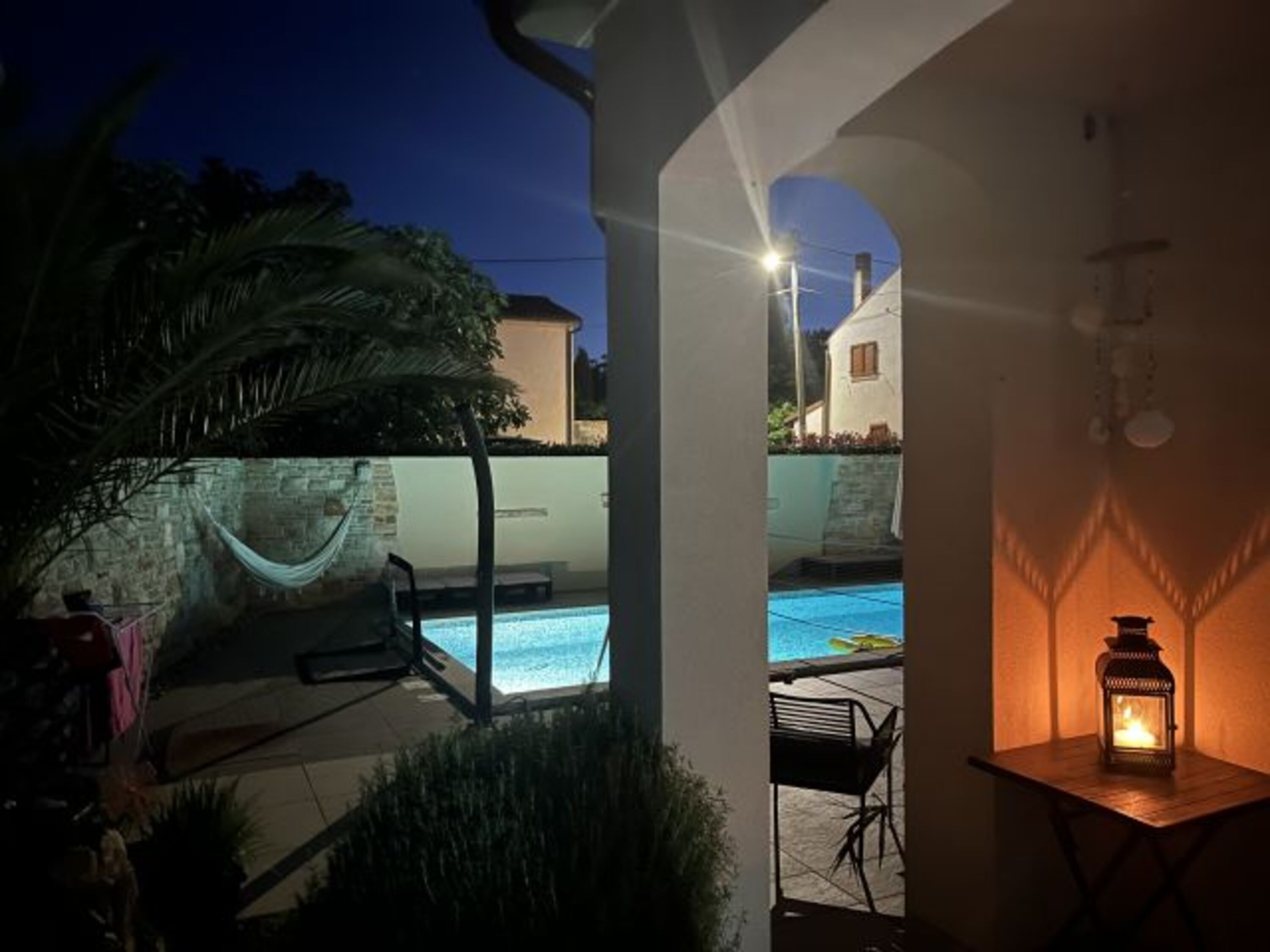 Blick von der Veranda auf d. großen beleuchteten Pool m. umlaufender Poolterasse