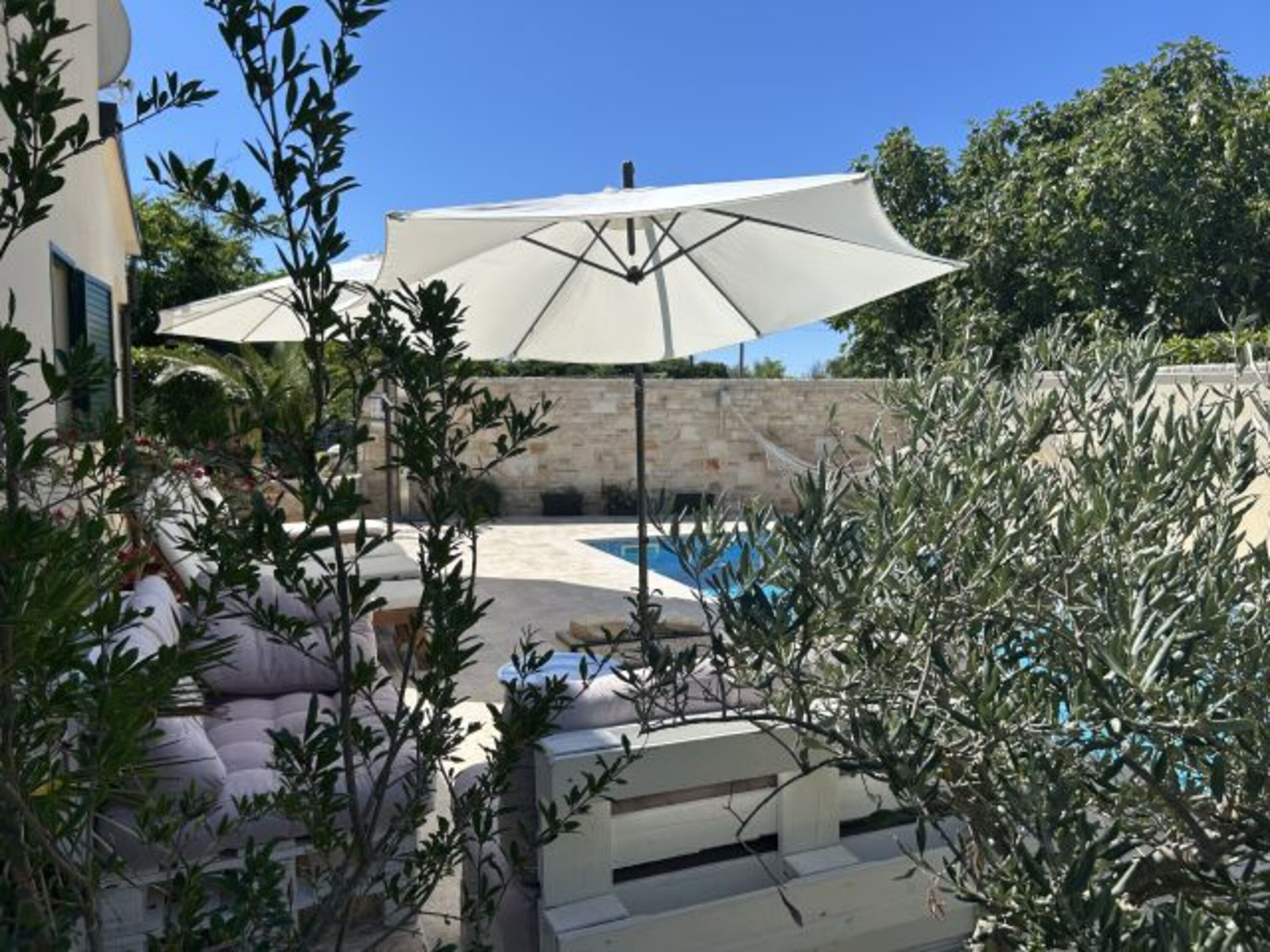 Blick auf den großen Pool mit umlaufender Poolterrasse und Liegestühle