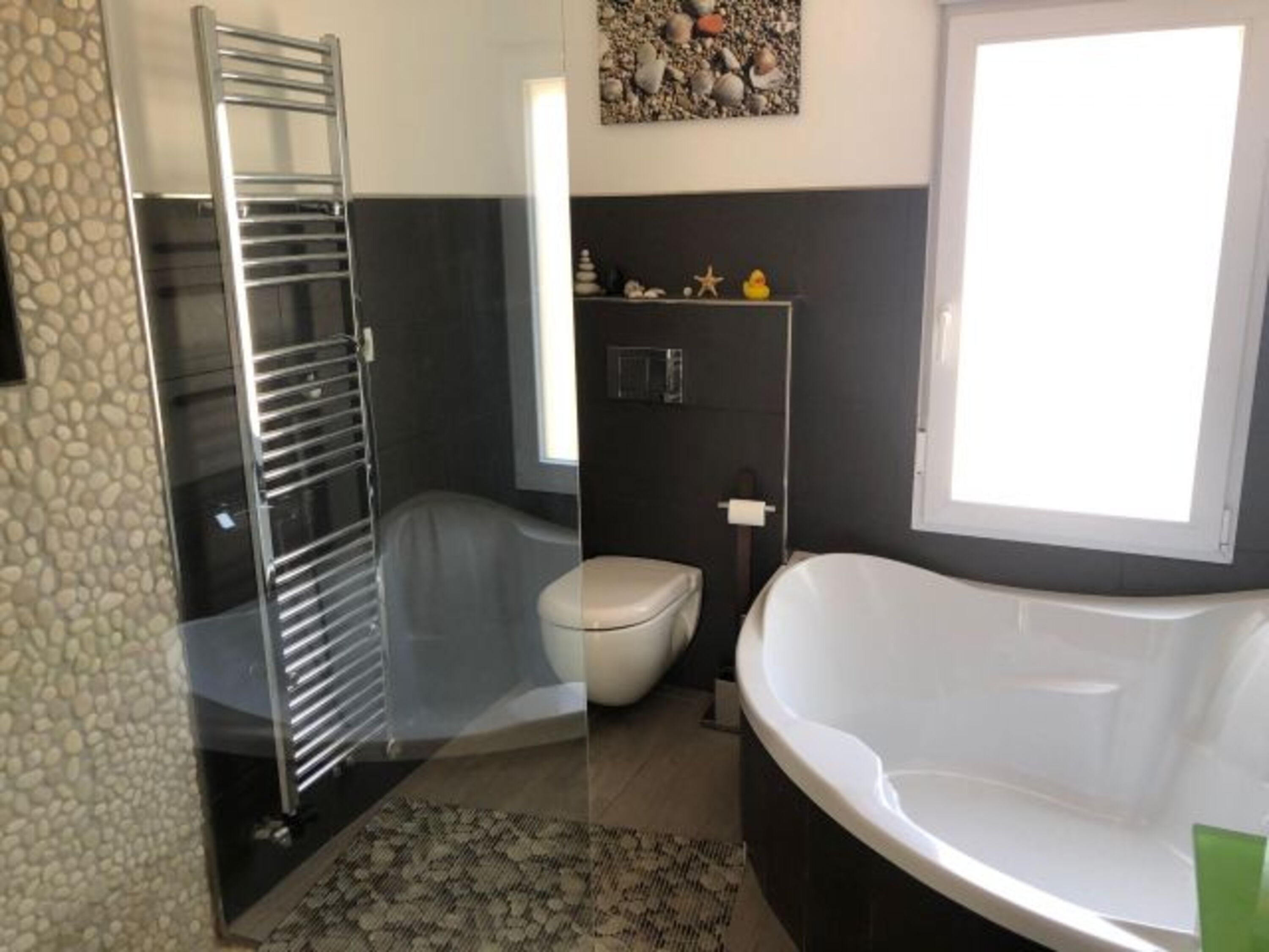 Eine Natursteindusche und große moderne Badewanne bieten das optimale Ambiente für Entspannung.
