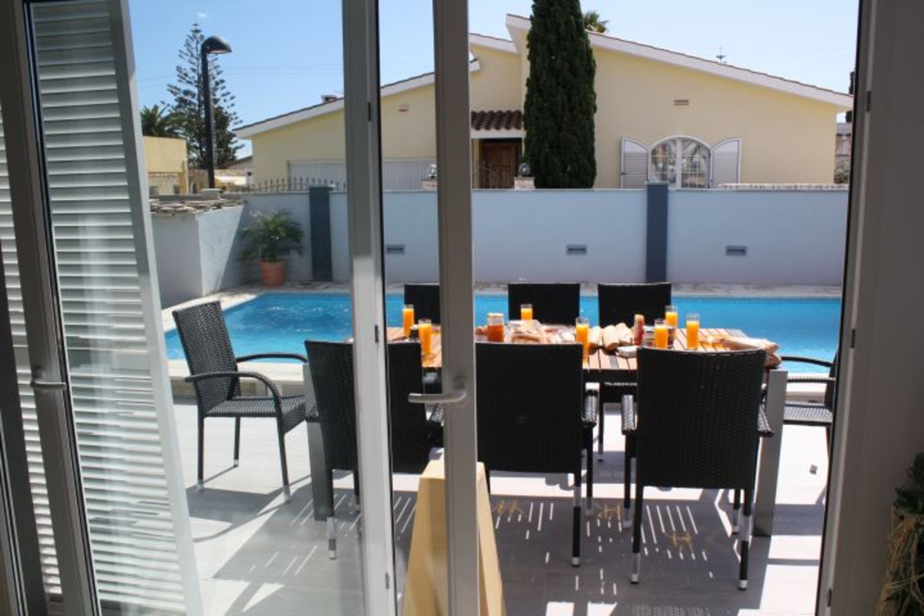 Blick aus dem Wohnzimmer hinaus auf Terrasse und Pool.