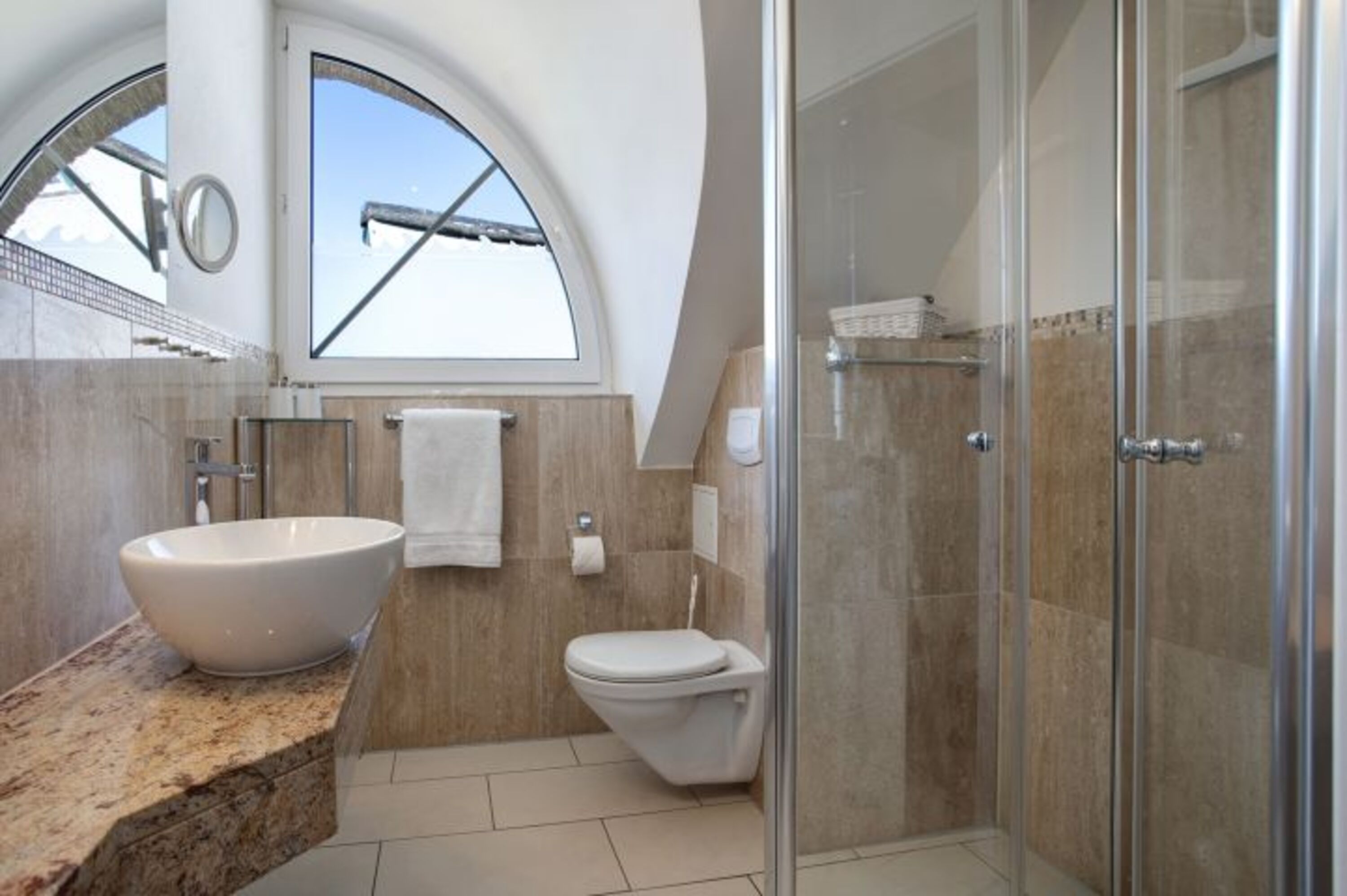 Modernes Badezimmer in Marmor mit stilvollem Waschbecken und bodengleicher Glasdusche.