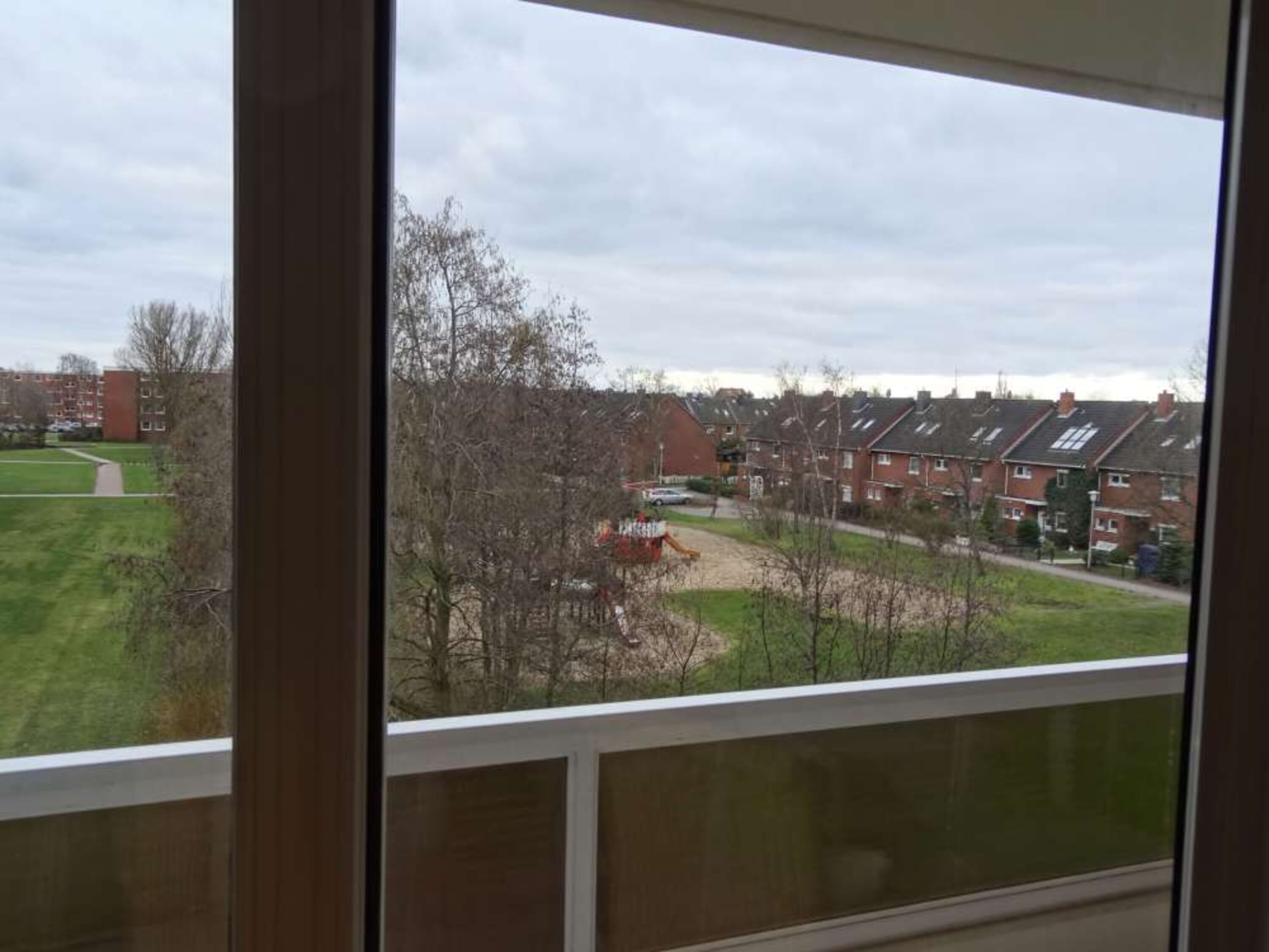 Blick vom Wohnzimmer auf eine ruhige Grünanlage