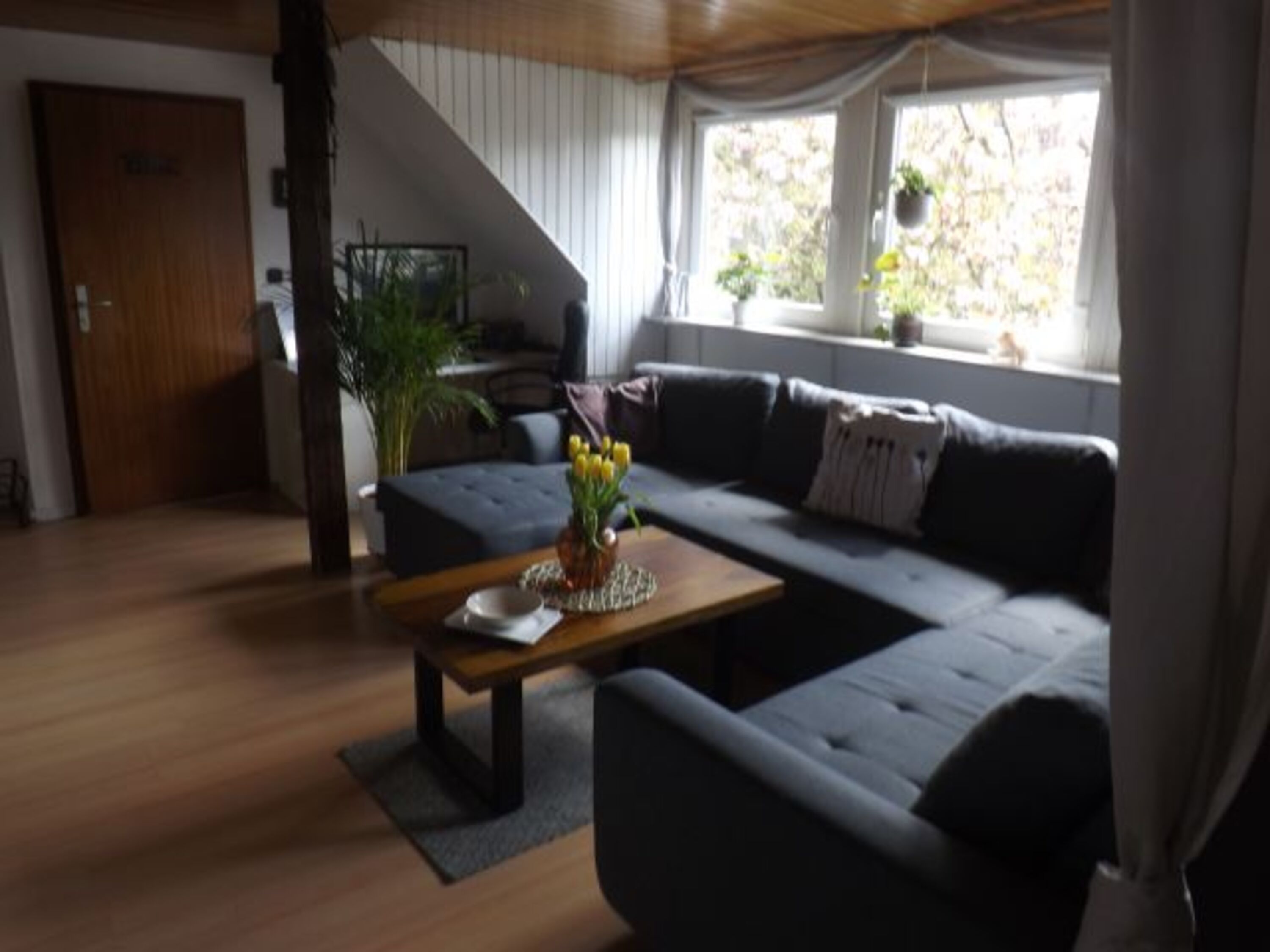 Wohnzimmer mit Sitzgruppe und massiven Holztisch und Arbeitsplatz
