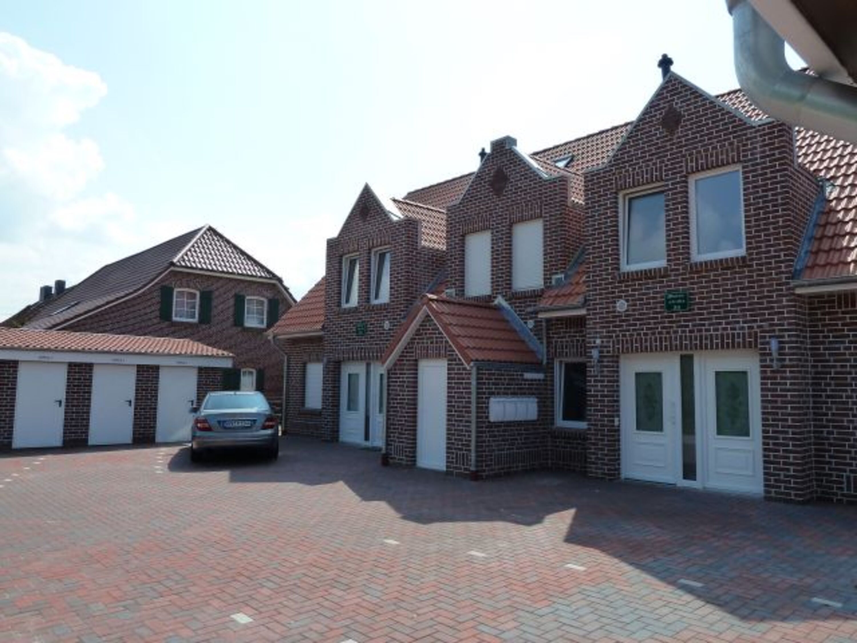 Haus mit Pkw-Stellplätzen und Gerätehäusern