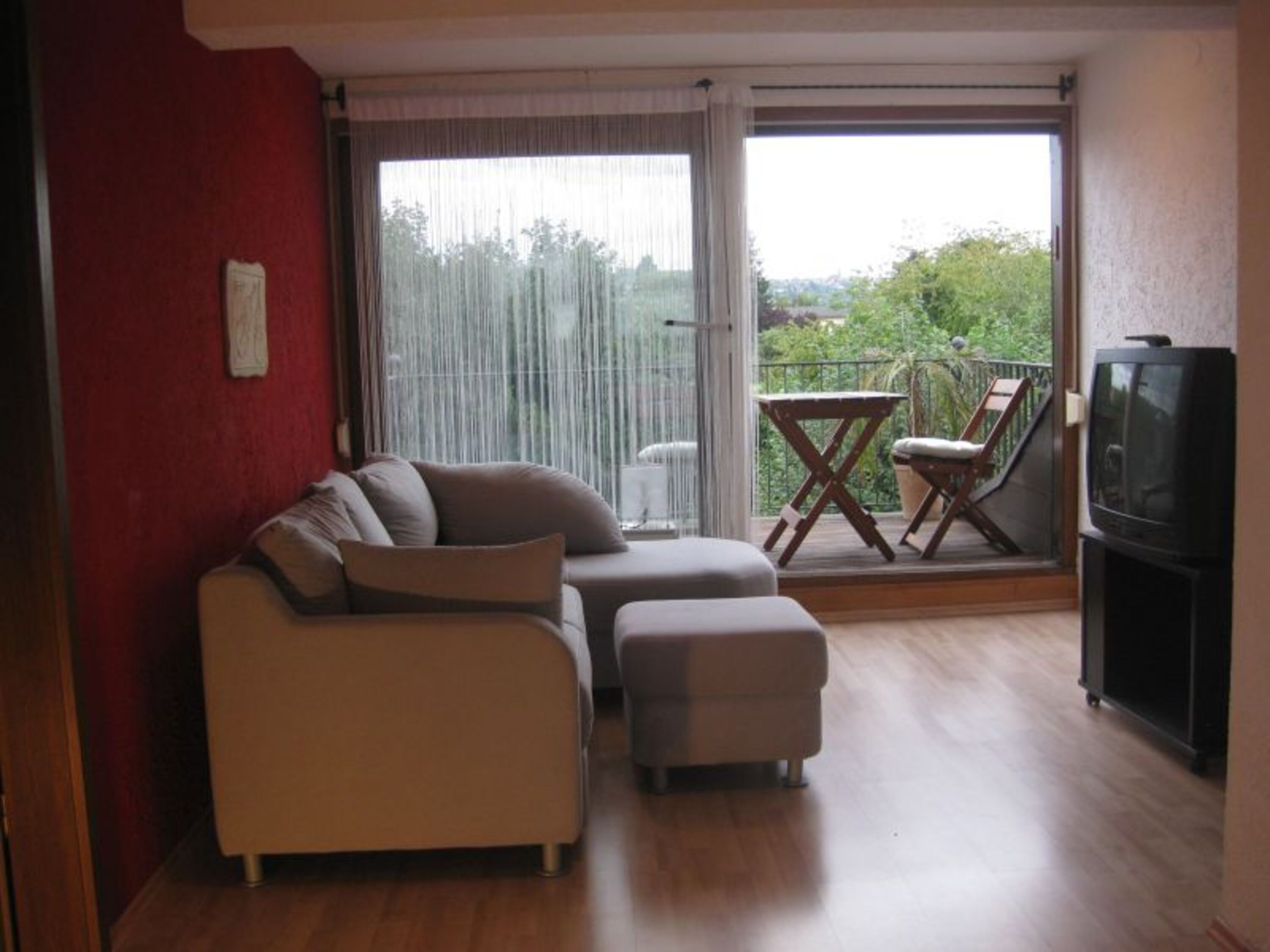 Wohnzimmer mit Fernseher und Internetanschluß, direkter Zugang zum Balkon mit Blick in den Garten.