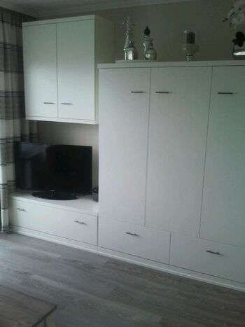 Appartmentwand mit Fernseher und Klappbett Wohnzimmer