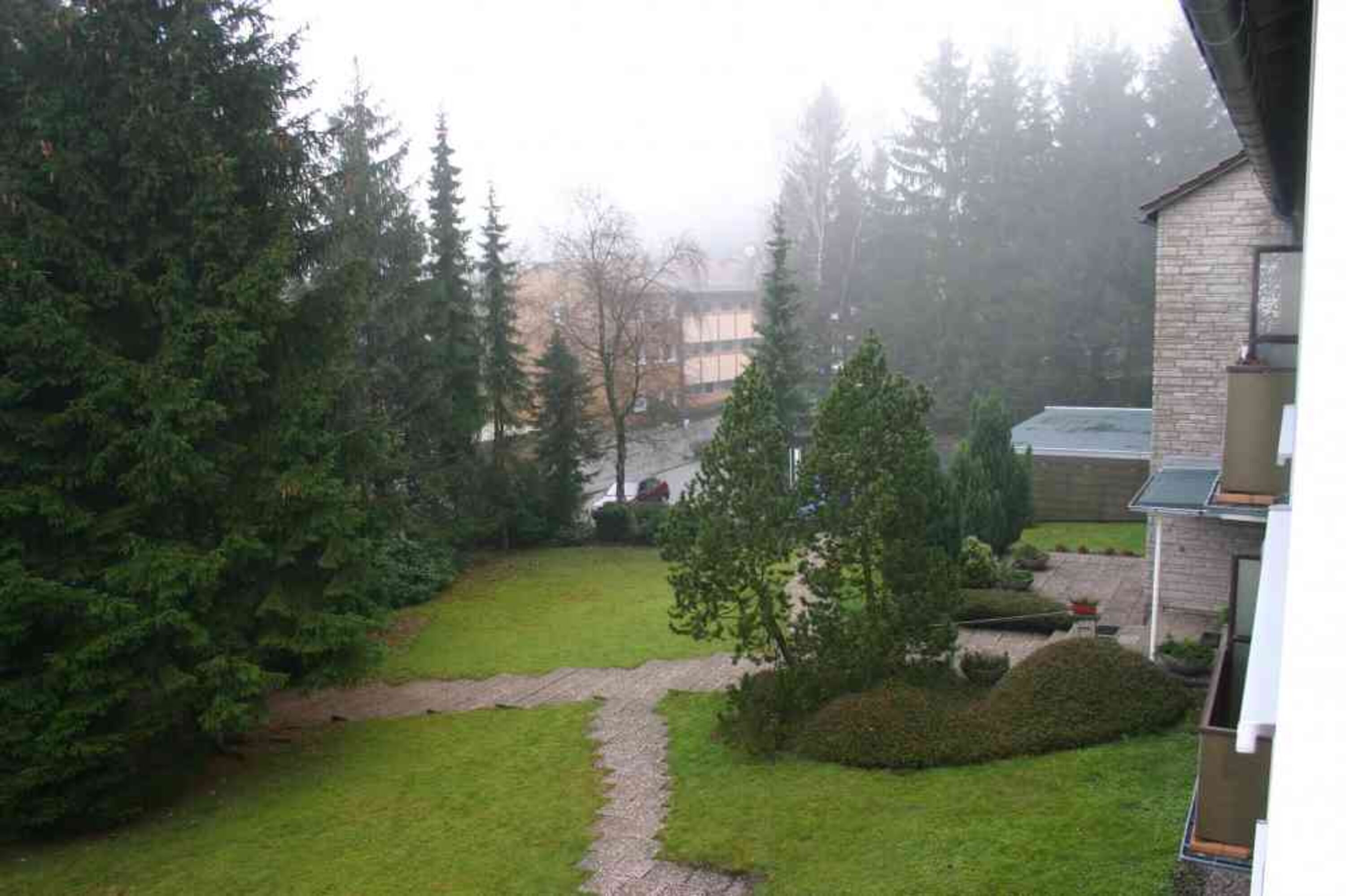Blick vom Balkon auf den Garten und den Eingang zum Haus